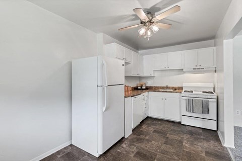 a kitchen with white appliances and a ceiling fan