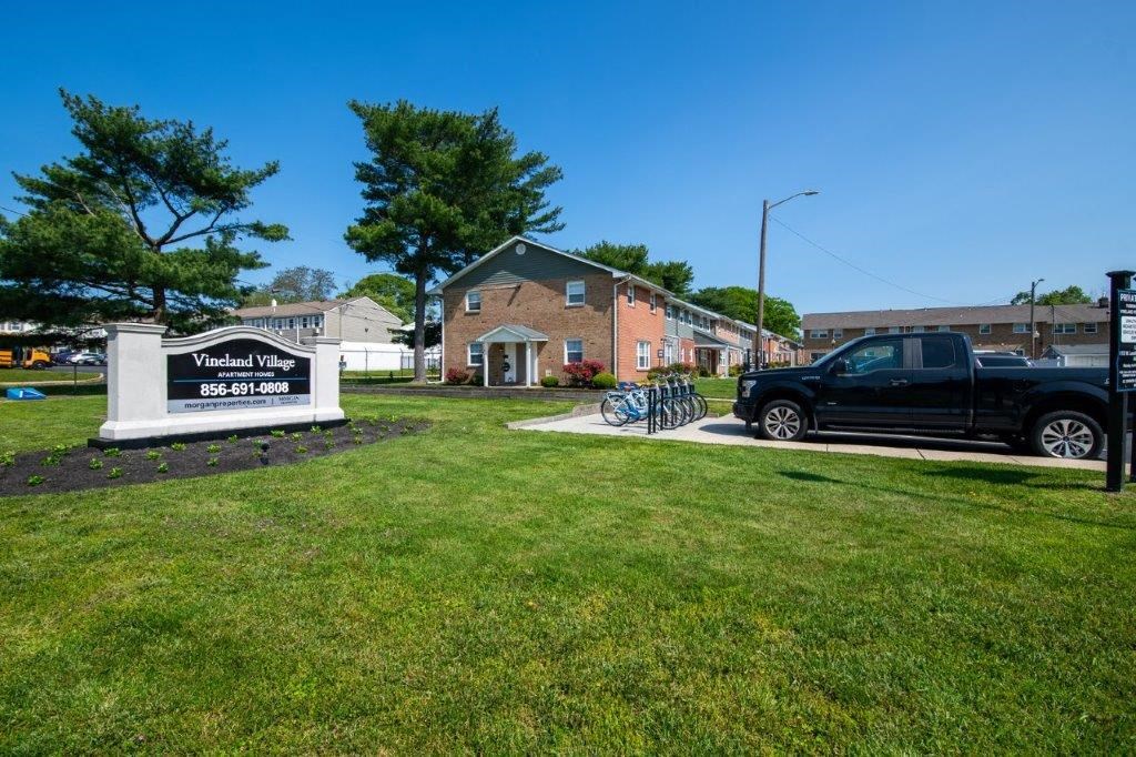 a black truck parked in front of a sign in a yard