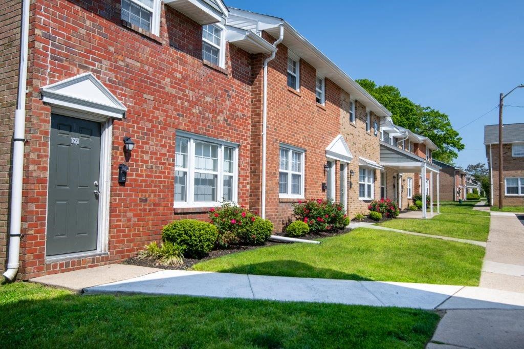a sidewalk in front of a brick apartment building