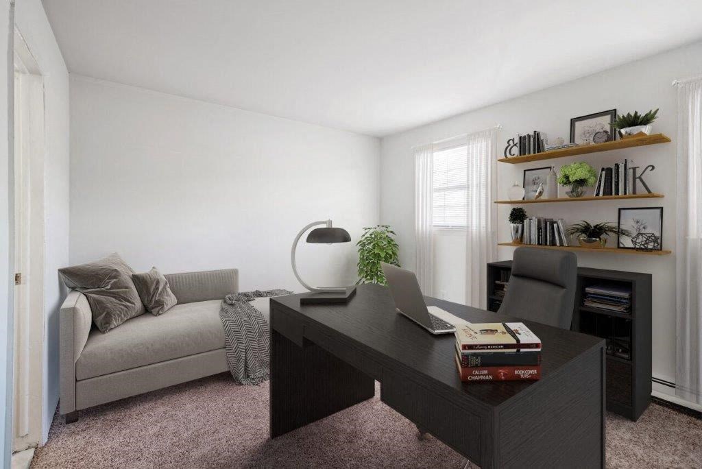 a living room with a couch and a desk with a laptop