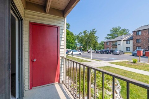 a red door on the balcony of a building with a parking lot