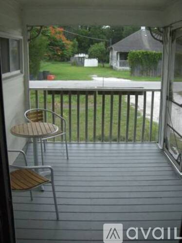 A balcony with a table and chairs overlooking a yard.