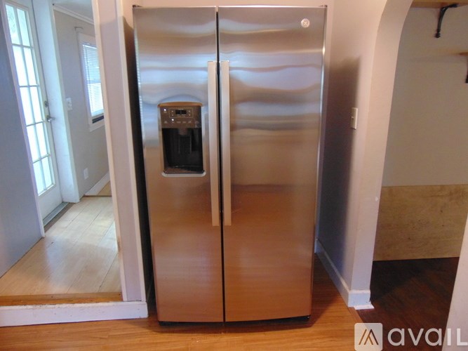 A stainless steel refrigerator with a water dispenser in the middle of the door.
