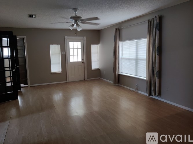 A spacious room with a ceiling fan and wooden flooring.