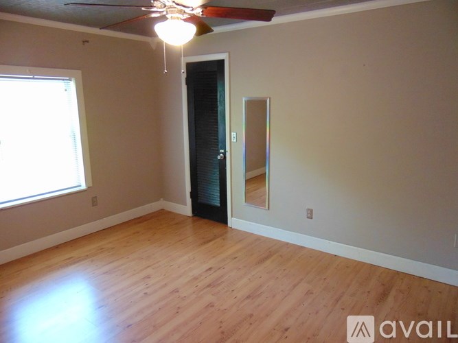 A room with a ceiling fan and a door with a mirror on the wall.