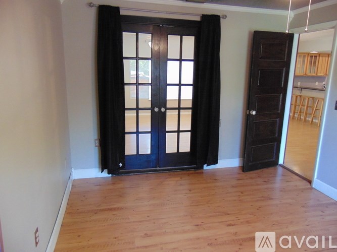 A room with a black door and wooden floor.
