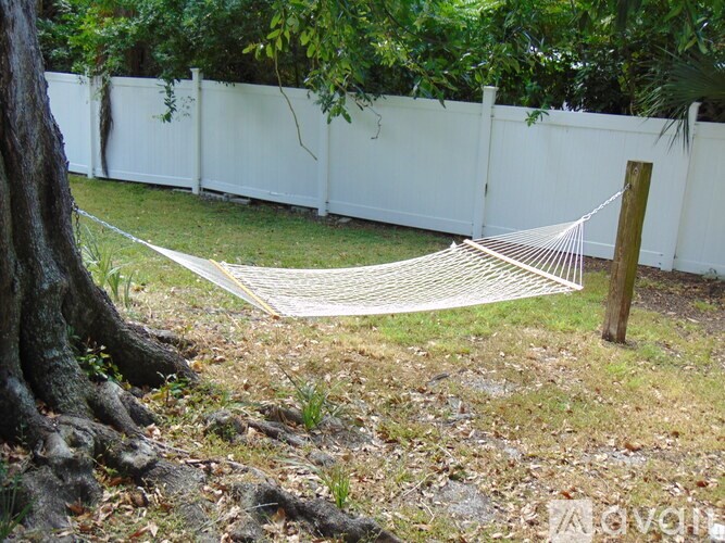 A hammock is strung between two wooden posts in a backyard.