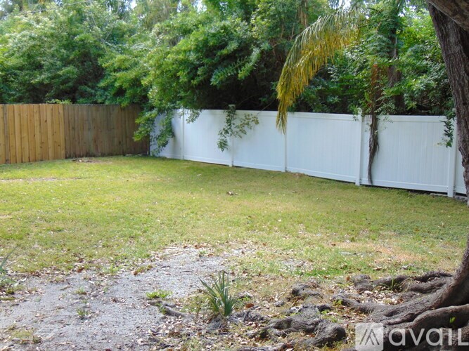 A backyard with a white fence and a tree.