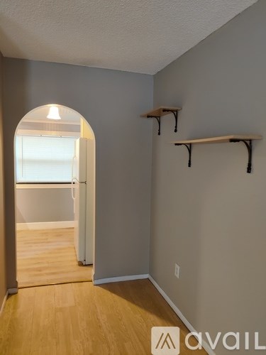 A room with a wooden floor and a wall-mounted shelf.