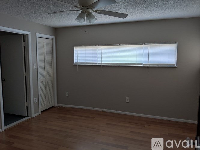 A room with a ceiling fan and a window with blinds.