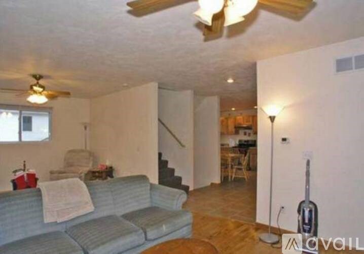 A living room with a couch, a fan, and a guitar.