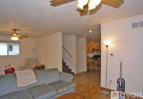 A living room with a couch, a fan, and a guitar.