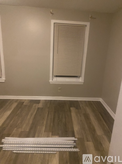 A room with wooden flooring and a window with blinds.
