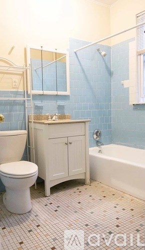 A white toilet sits next to a sink in a blue-tiled bathroom.