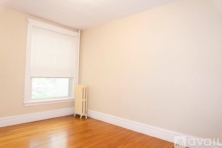 A room with a window and a white radiator on the floor.