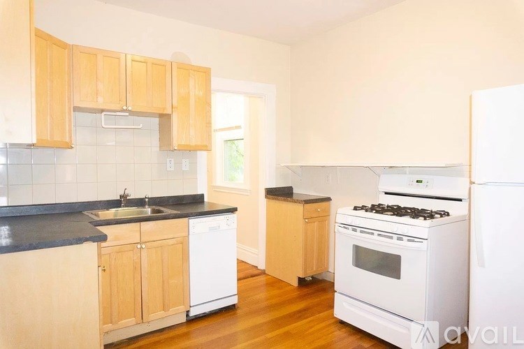 A kitchen with wooden cabinets and a white dishwasher.