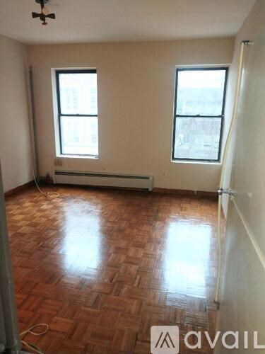 A room with wooden flooring and two windows.