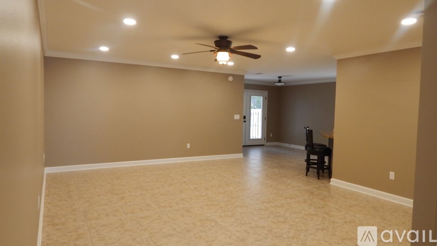 A spacious room with a ceiling fan and a chair.