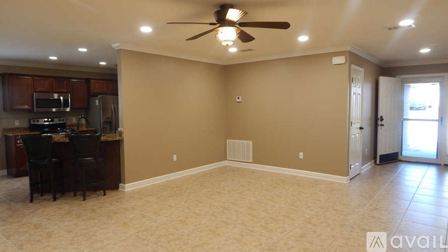 A spacious room with a ceiling fan and a kitchen area with a microwave and oven.