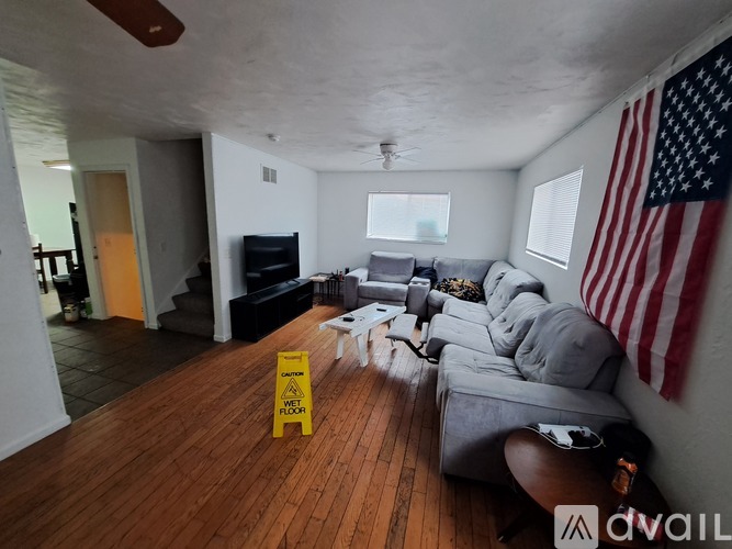 A living room with a yellow caution sign on the floor.