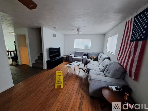 A living room with a yellow caution sign on the floor.