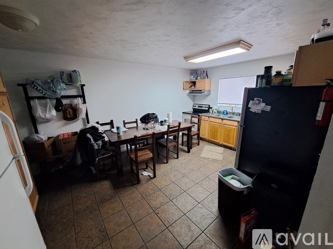 A kitchen area with a table and chairs, a refrigerator, and a counter with various items on it.