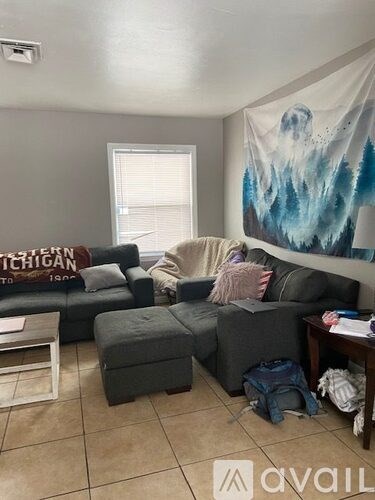 A living room with a grey couch and a banner on the wall.