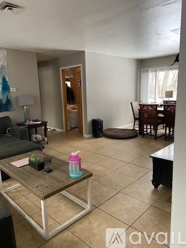 A living room with a couch, coffee table, and a dining table.