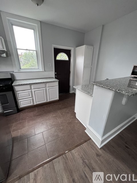 A kitchen with white cabinets and a brown floor.