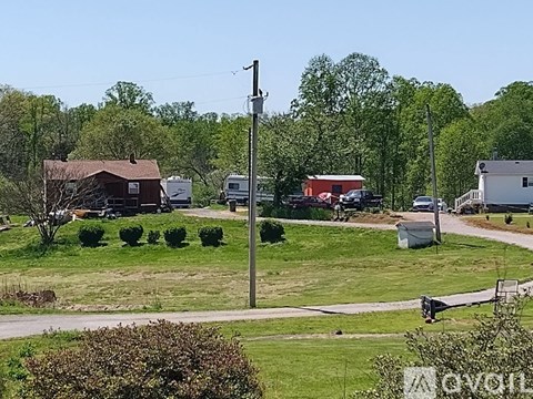 A rural landscape with a house, trees, and a utility pole.