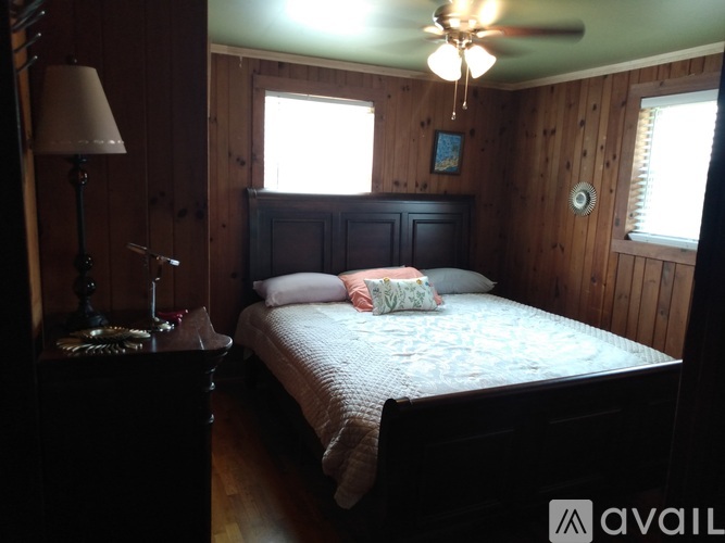 A bedroom with a bed, nightstand, lamp, and a window.