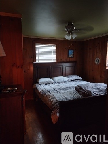 A bedroom with a bed, nightstand, and window.