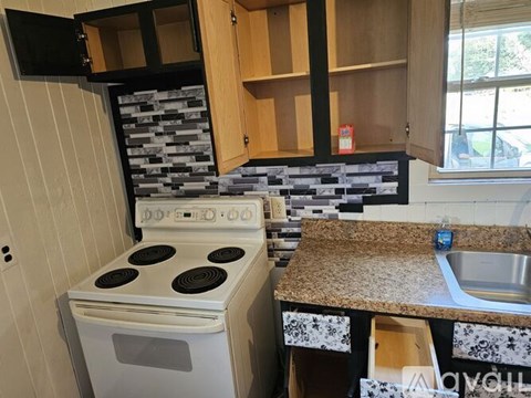 A kitchen with a white stove and wooden cabinets.