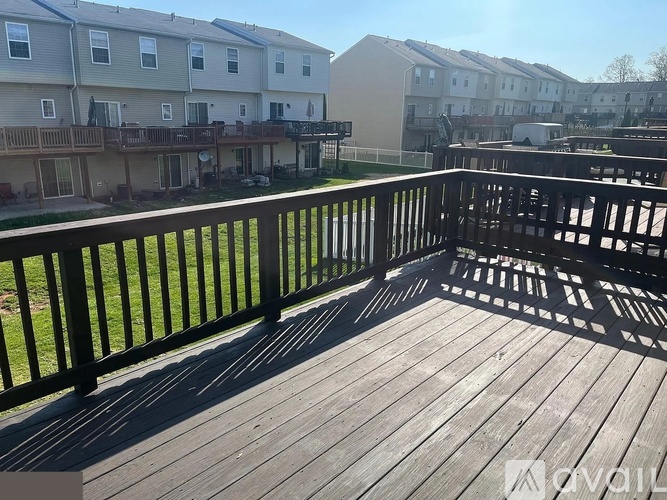 A wooden deck with a railing and apartment buildings in the background.