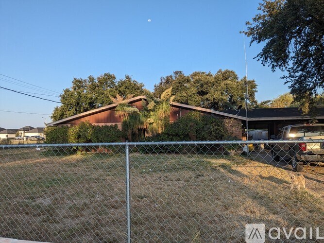 A chain link fence with a house and trees in the background.