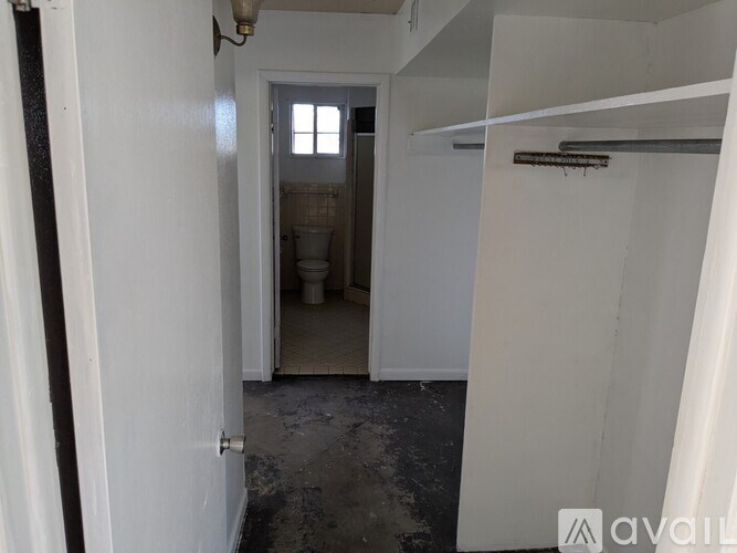 A hallway with a door at the end and a cabinet in the middle.