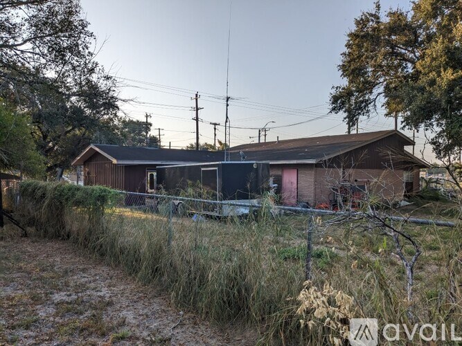 A house with a fence and a tree in front of it.