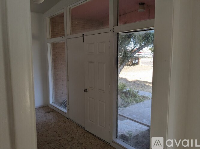 A room with a white door and a window showing an outdoor view.