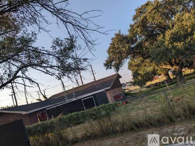 A house with a red door is surrounded by trees and grass.