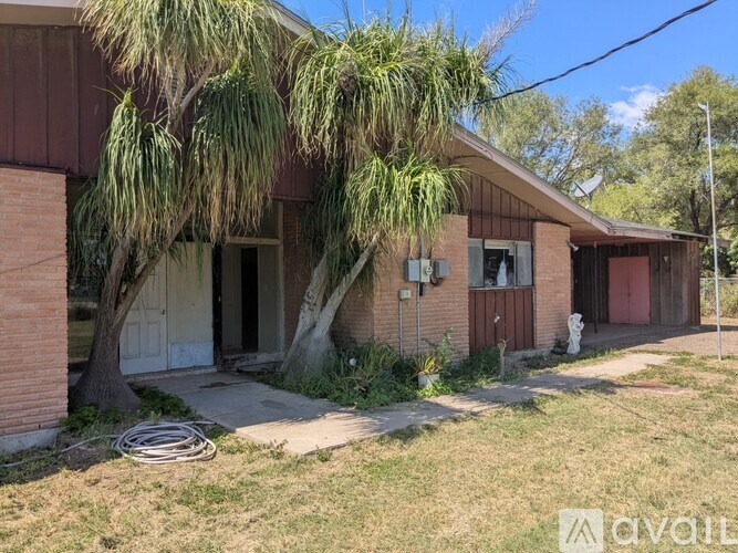 A fenced area with a tree and a building in the background.