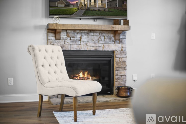 A white chair with wooden legs is in front of a fireplace.