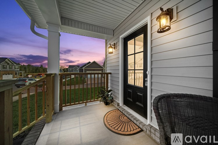 A porch with a black door and a wicker chair.