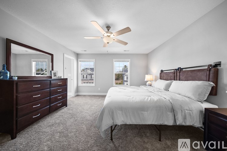 A bedroom with a large bed, a dresser, and a ceiling fan.