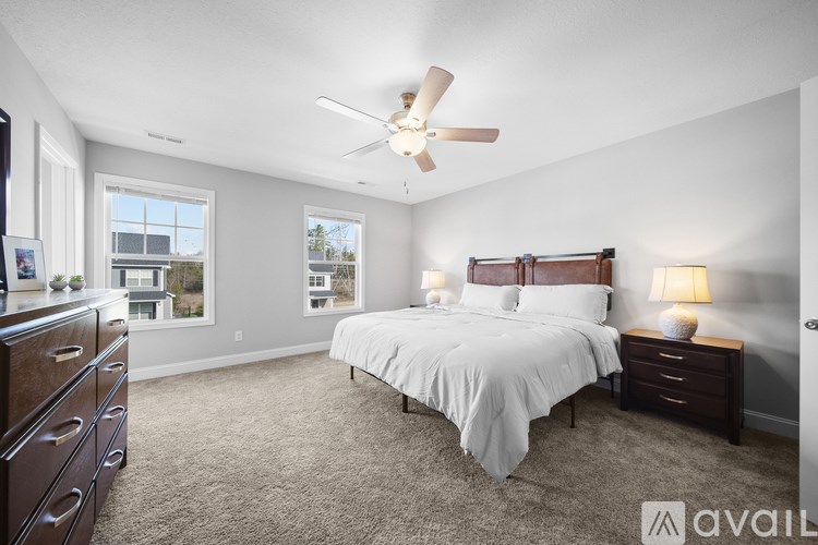 A bedroom with a large bed, a ceiling fan, and a dresser.
