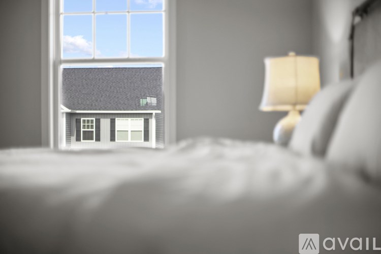 A bedroom with a large window overlooking a house.