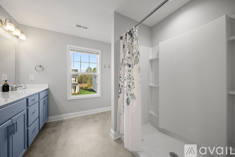 A bathroom with a window showing a view of a tree and a blue cabinet.