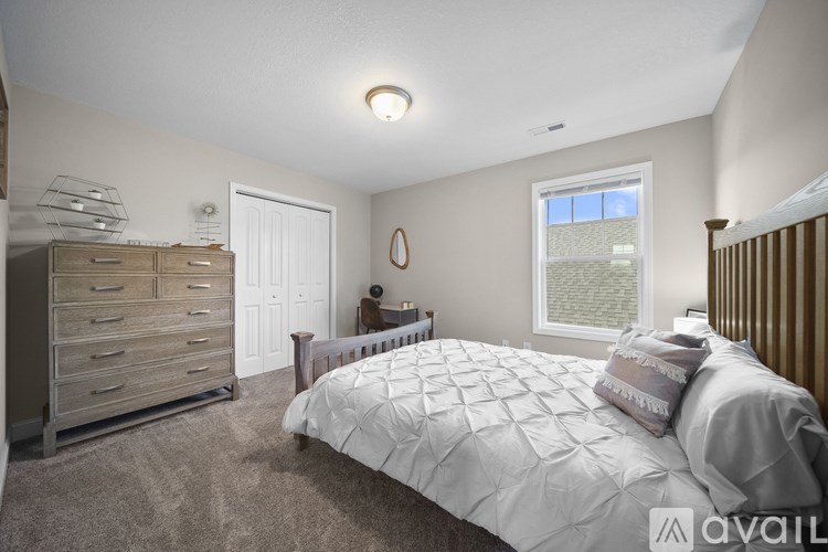 A bedroom with a bed, dresser, and window.