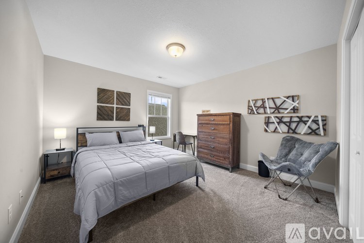 A bedroom with a bed, nightstand, and chair.