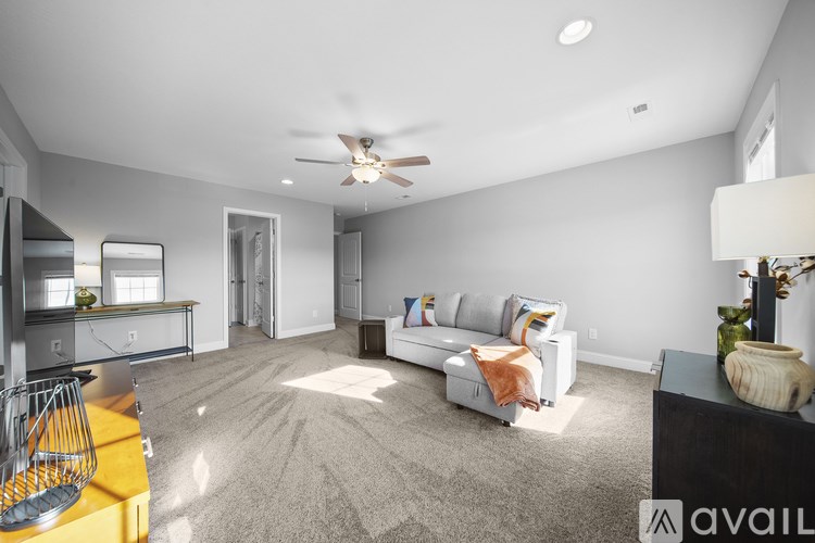 A spacious living room with a white sofa and a ceiling fan.