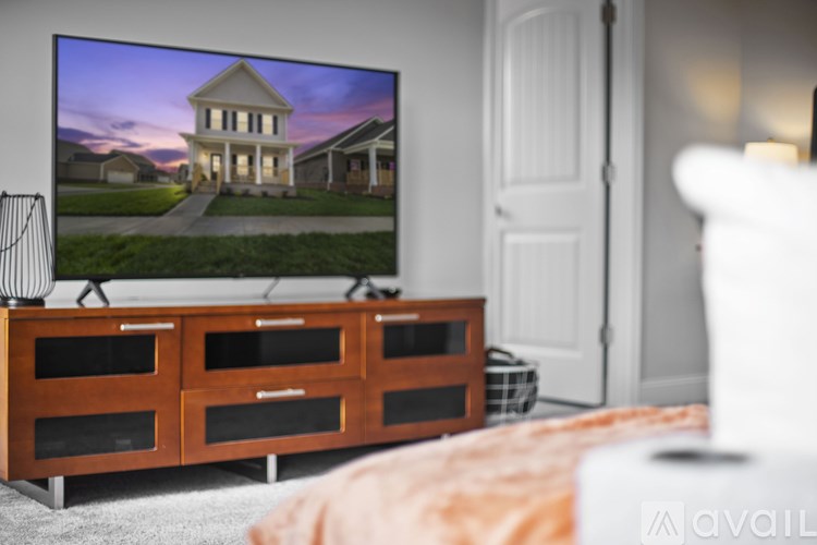 A large television is mounted on a wall above a wooden cabinet with two drawers.